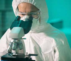 Ricercatrice in tuta sterile osserva un campione al microscopio